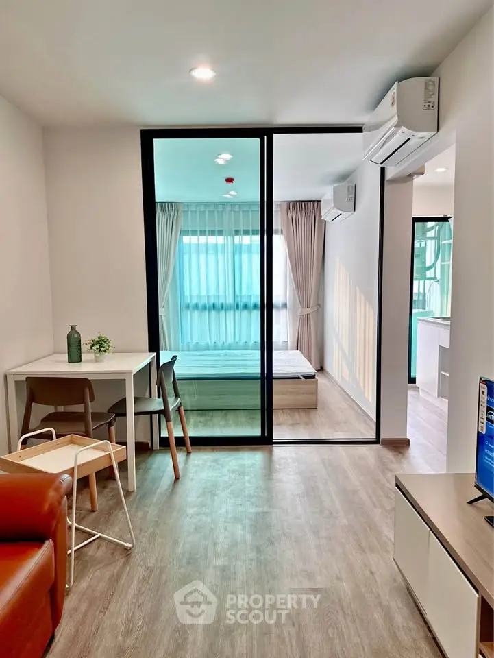 Modern open-plan living room with sliding glass doors to bedroom, featuring stylish decor and natural light.