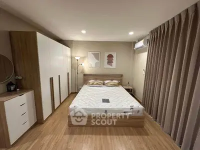Modern bedroom with wooden flooring, stylish furniture, and ambient lighting.