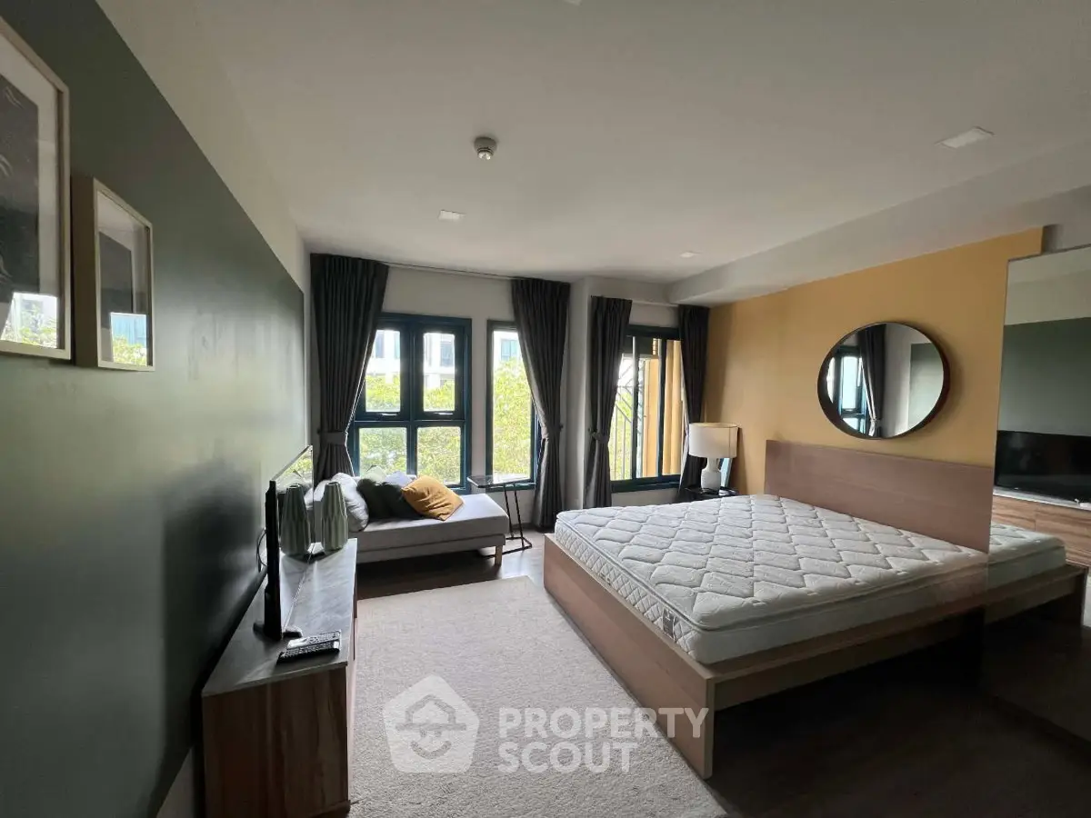 Spacious bedroom with large windows and modern decor, perfect for relaxation and comfort.