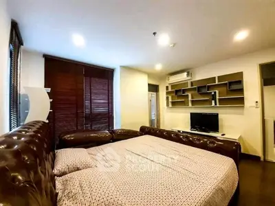 Spacious living room with modern decor and large leather sofa in a stylish apartment.