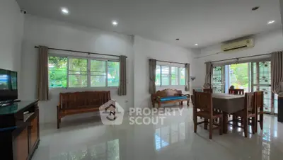Spacious living room with elegant wooden furniture and large windows offering garden views.