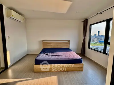 Spacious bedroom with city view and modern wooden flooring.