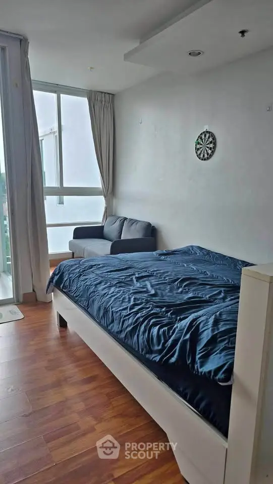 Modern bedroom with wooden flooring and large window for natural light.