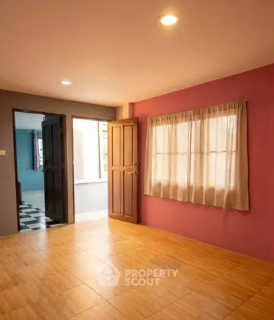Spacious empty room with wooden flooring and natural light, ideal for customization.