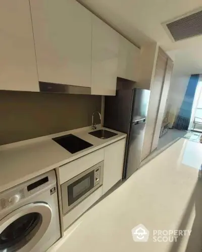 Modern kitchen with sleek appliances and ample storage in a bright, contemporary apartment.