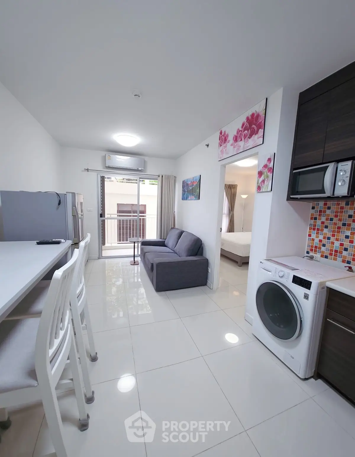 Modern apartment interior with open layout, featuring kitchen, living area, and washing machine.