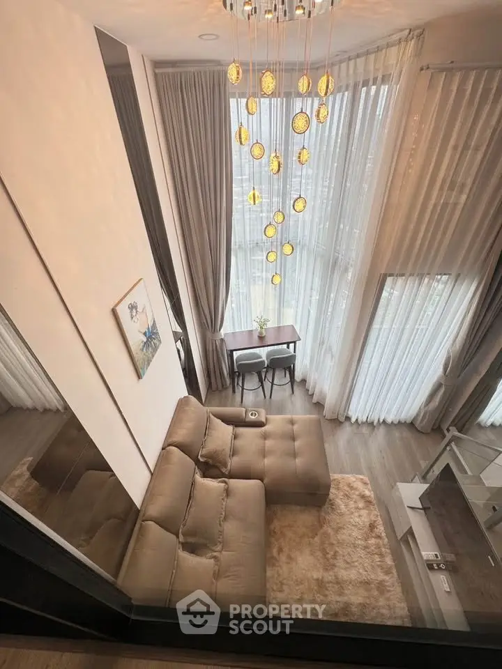 Luxurious high-ceiling living room with elegant chandelier and floor-to-ceiling windows.