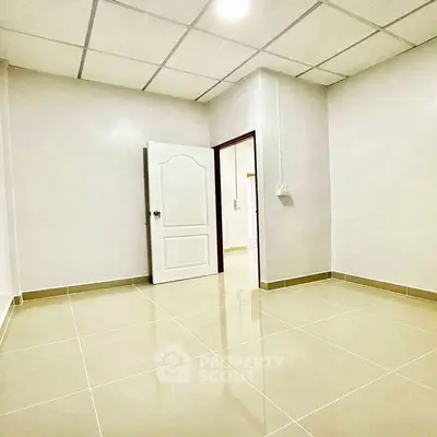 Spacious empty room with glossy tiled floor and open door, ready for customization.