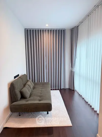 Modern living room with stylish sofa and floor-to-ceiling curtains, perfect for relaxation.