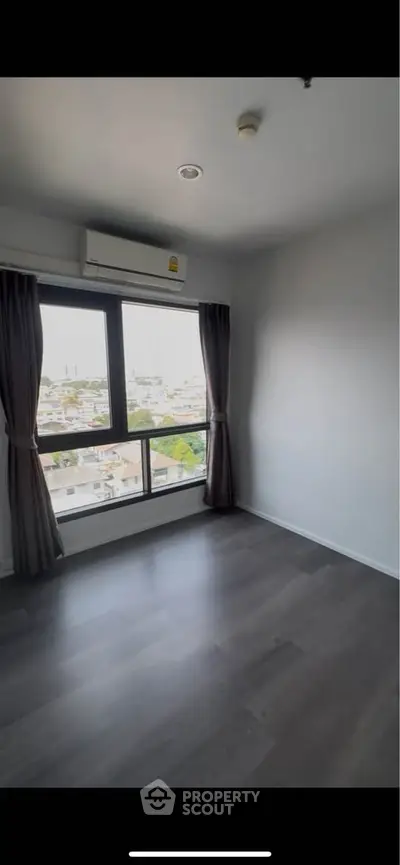 Bright empty room with large window offering city view, ideal for customization.