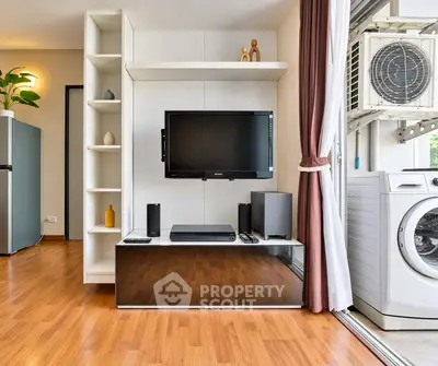 Modern living room with sleek entertainment center and adjacent laundry area, featuring a washing machine and air conditioning unit.