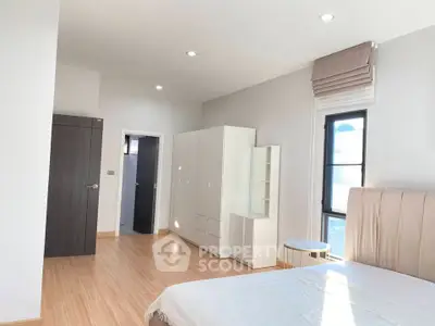 Spacious and bright bedroom with modern furnishings and large windows.