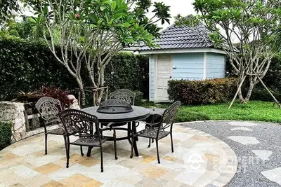 Charming garden with patio furniture and lush greenery, perfect for outdoor relaxation.