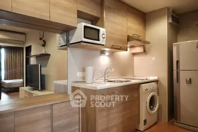 Modern compact kitchen with wooden cabinets and built-in appliances in cozy apartment.