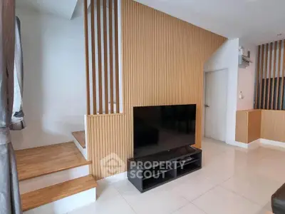 Modern living room with sleek TV setup and stylish wooden accents