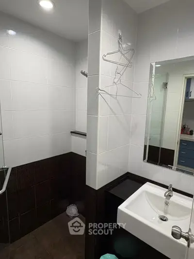 Modern bathroom with sleek sink and tiled walls, featuring a minimalist design and ample lighting.