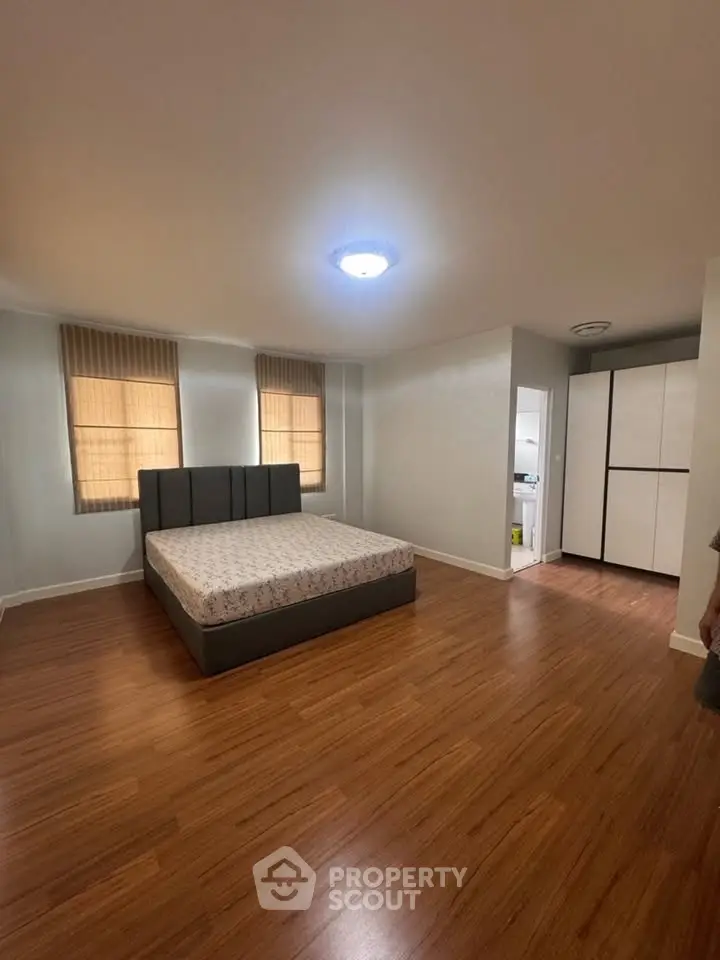 Spacious bedroom with modern bed and wooden flooring in a cozy apartment.