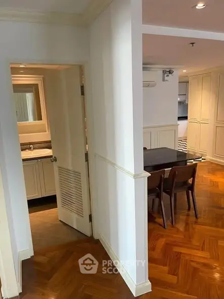 Spacious dining area with elegant wooden flooring and adjacent bathroom in modern apartment.