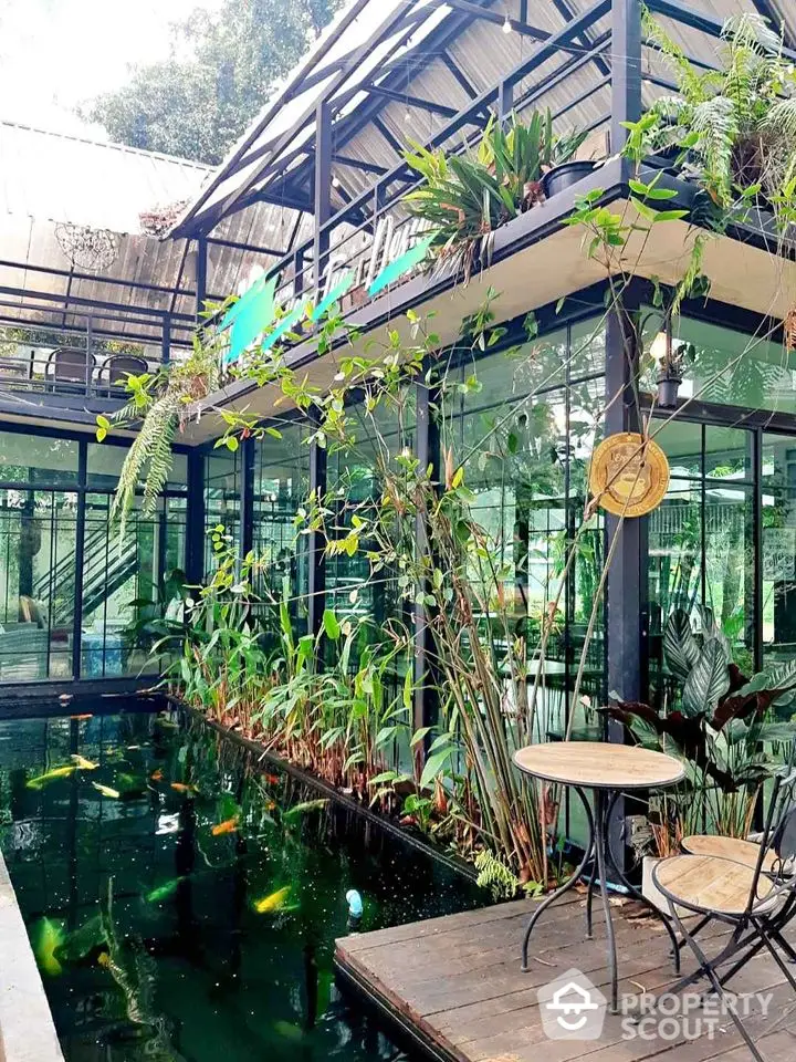 Modern glass building with koi pond and lush greenery, perfect for serene living or commercial space.