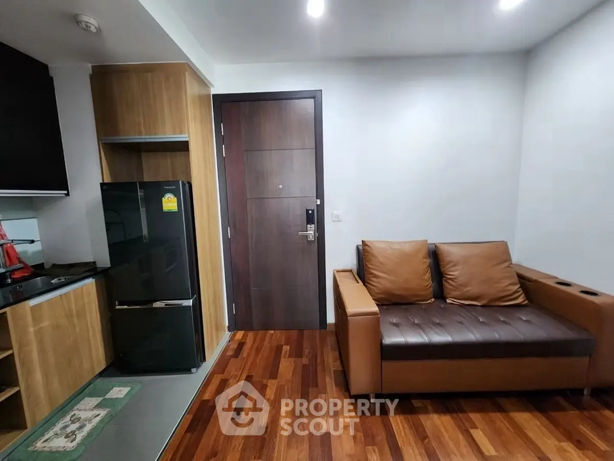 Modern apartment interior with sleek kitchen and cozy living area featuring wooden flooring and stylish furniture.