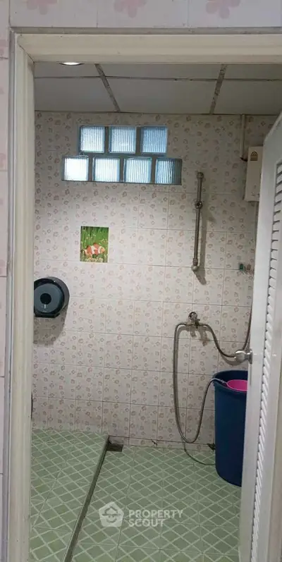 Cozy bathroom with tiled walls and floor, featuring a shower and a small window for natural light.