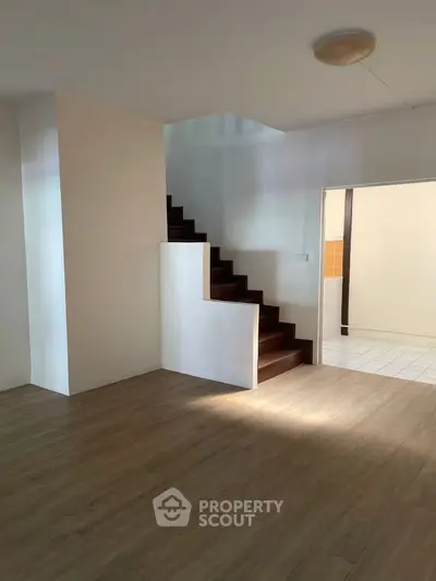 Spacious interior with wooden flooring and modern staircase, ideal for contemporary living.