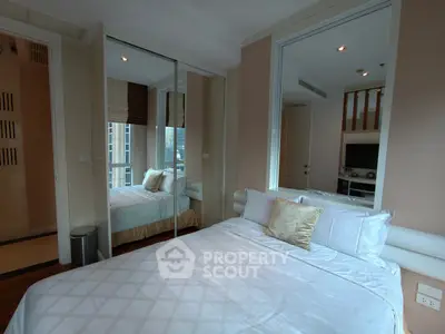 Modern bedroom with mirrored closet and city view, featuring elegant bedding and neutral decor.