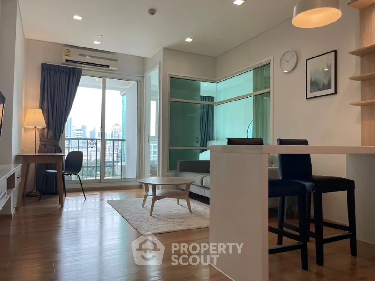 Modern living room with balcony and city view, featuring stylish furniture and open layout.