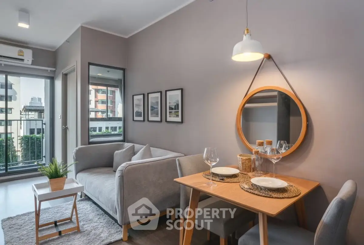 Modern living room with cozy dining area and balcony view in urban apartment.