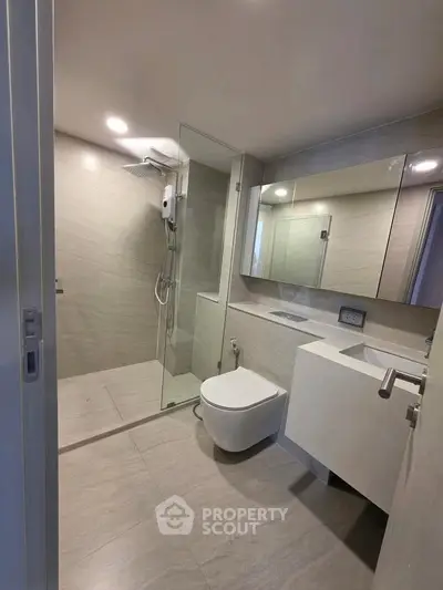 Modern bathroom with sleek design, featuring a glass shower enclosure and wall-mounted toilet.