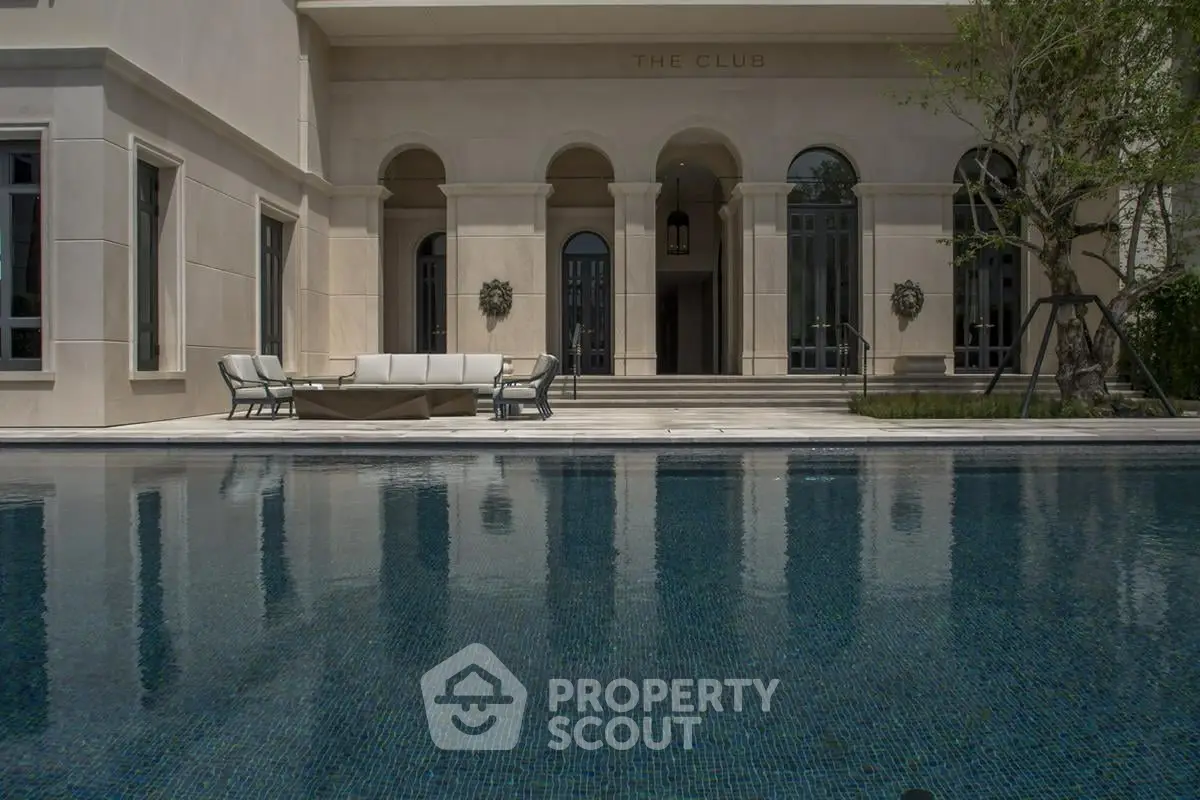 Luxurious poolside view of elegant club building with arched windows and stylish outdoor seating.