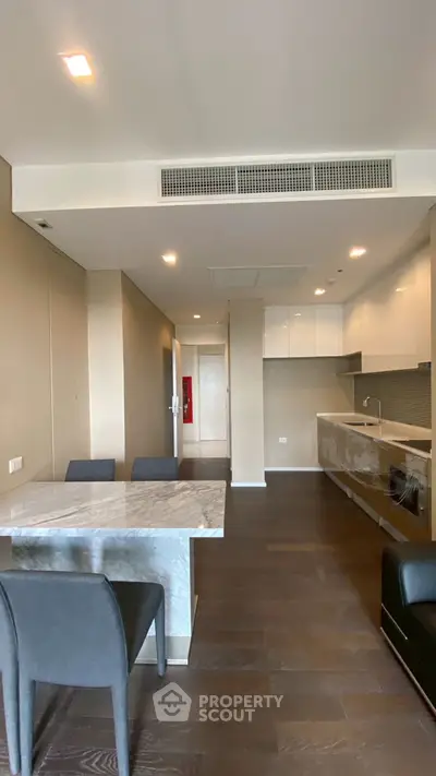 Modern open-layout kitchen with sleek cabinetry and dining area in a stylish apartment.
