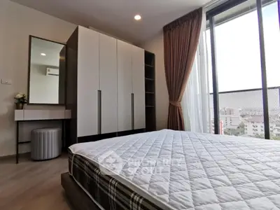 Modern bedroom with large window and stylish furniture in a high-rise apartment.