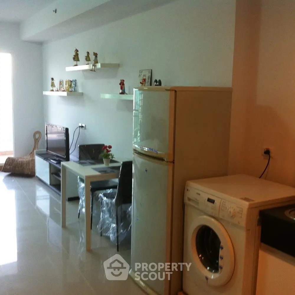 Modern living room with sleek furniture and appliances, including a washing machine and fridge.