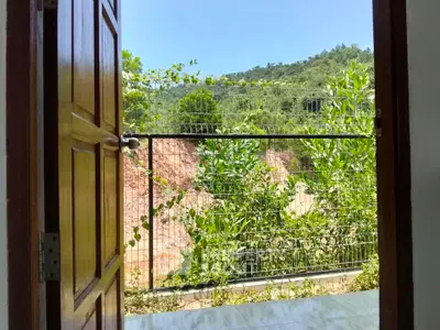 Charming balcony with lush greenery and scenic mountain view, perfect for relaxation.