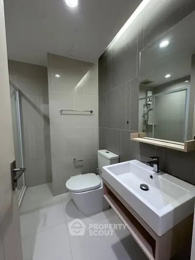 Modern bathroom with sleek fixtures and contemporary design, featuring a spacious shower and elegant sink.