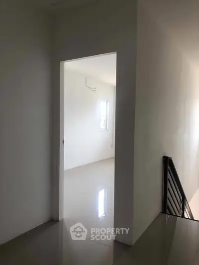 Minimalist interior hallway leading to a bright room with glossy flooring and natural light.