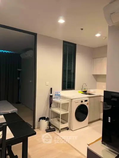 Modern apartment interior with compact kitchen and laundry area, featuring sleek design and efficient use of space.