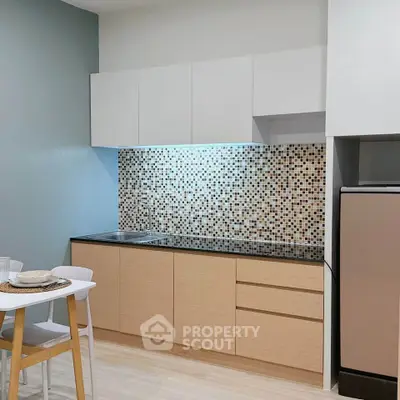 Modern kitchen with sleek cabinetry and mosaic backsplash in a stylish apartment.