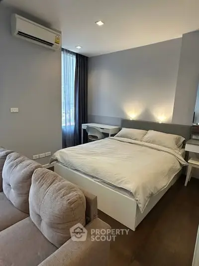 Modern bedroom with cozy bed and stylish decor, featuring natural light and sleek furnishings.