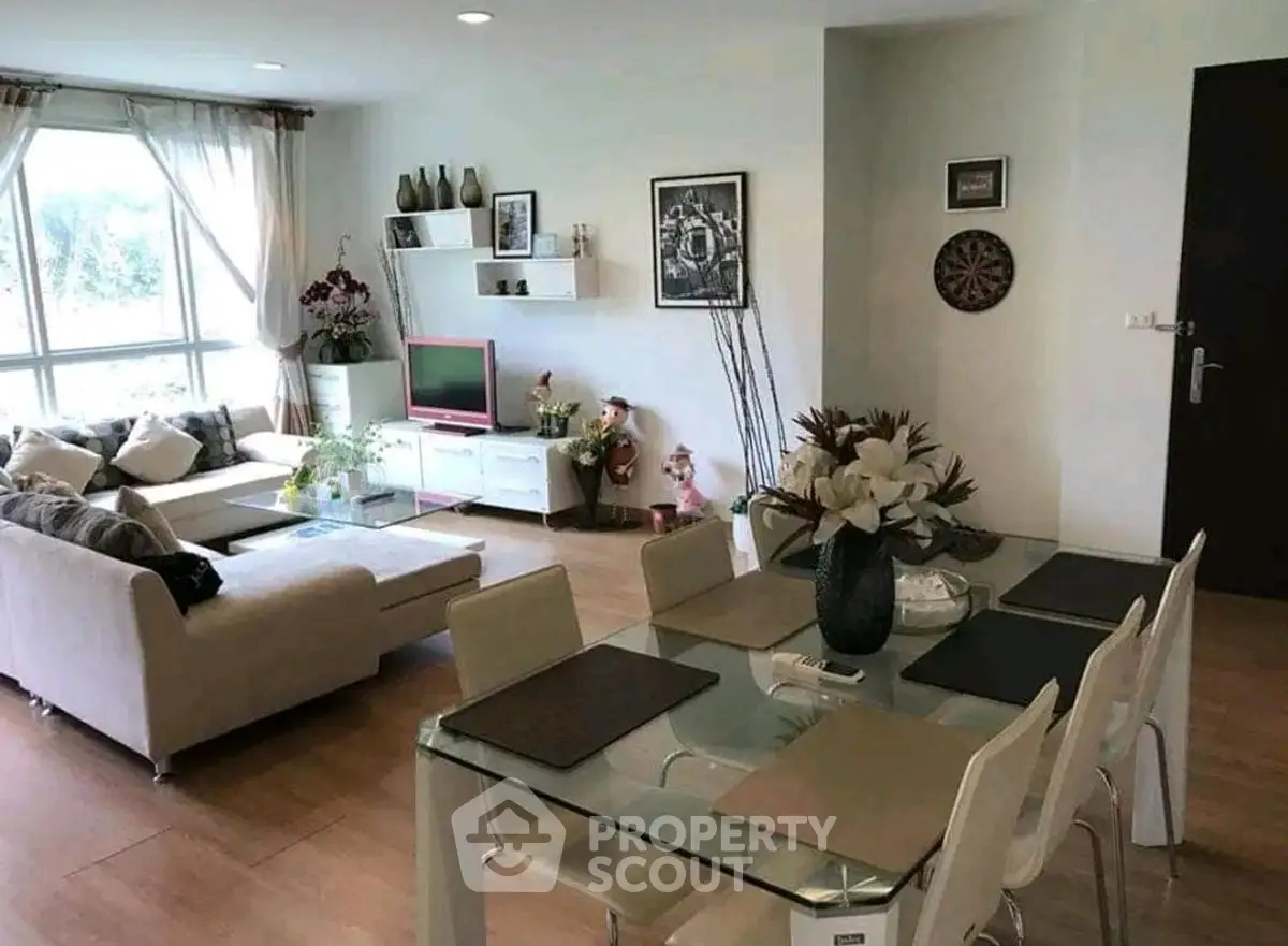 Spacious living room with modern decor and dining area, featuring large windows and stylish furniture.