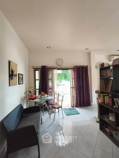 Charming living room with natural light, cozy seating, and access to a balcony, perfect for relaxation.