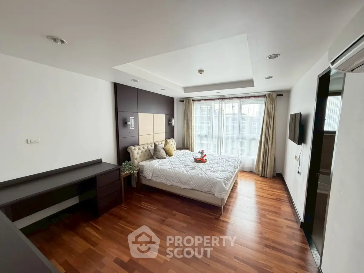 Spacious bedroom with modern decor and large windows offering natural light.