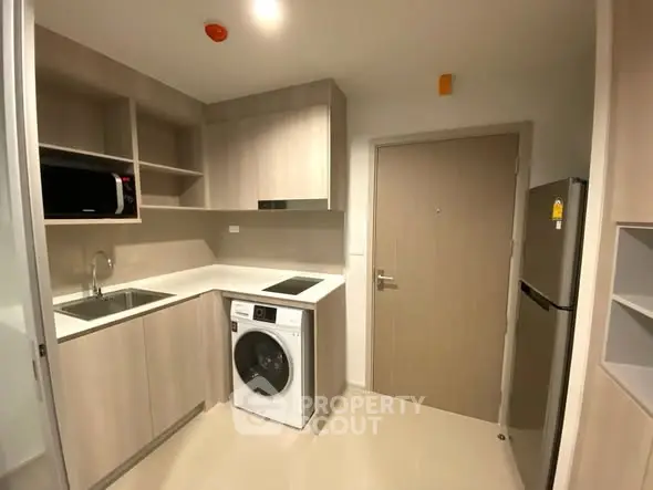 Modern kitchen with sleek cabinetry, washing machine, and stainless steel appliances.