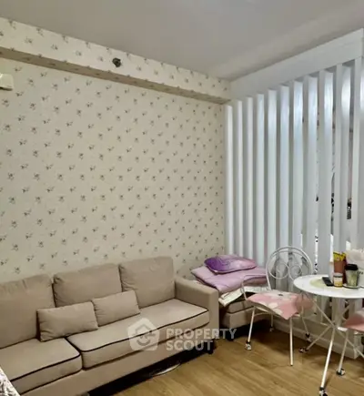 Cozy living room with floral wallpaper and beige sofa, perfect for relaxation.