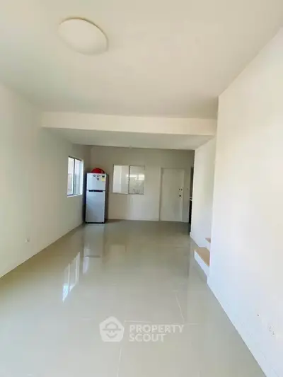 Spacious minimalist living room with glossy tiled floors and natural light.