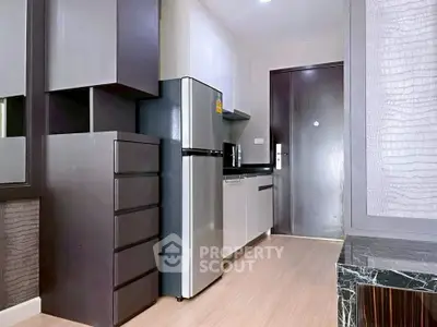 Modern kitchen with sleek cabinetry and stainless steel fridge in compact apartment.