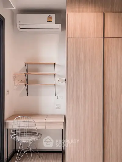 Modern study nook with wooden desk, shelves, and air conditioning in a stylish apartment.