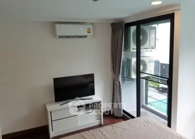Modern bedroom with air conditioning and balcony access in urban apartment.