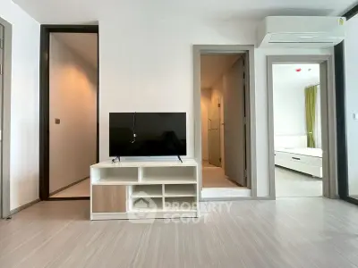 Modern living room with TV and air conditioning, leading to bedroom and bathroom.